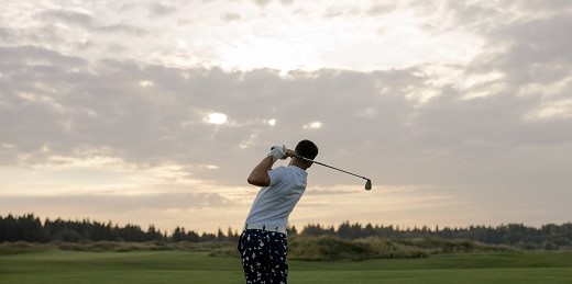 Individual taking a golf swing.